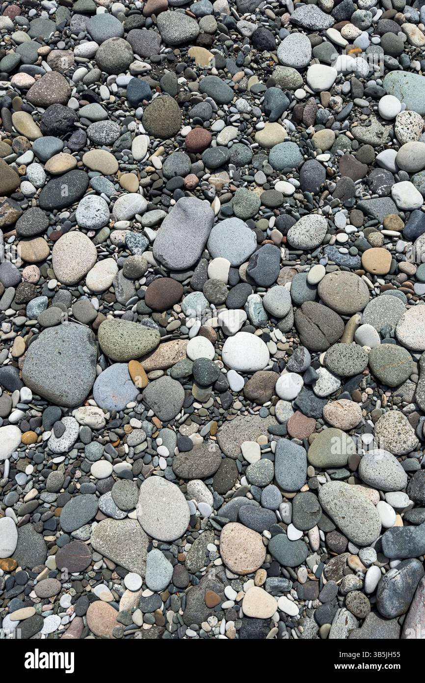 Primo piano di ciottoli colorati e lisci su una spiaggia. Struttura naturale e sfondo in pietra, nessuna gente, dettagli astratti sulla costa. Foto Stock