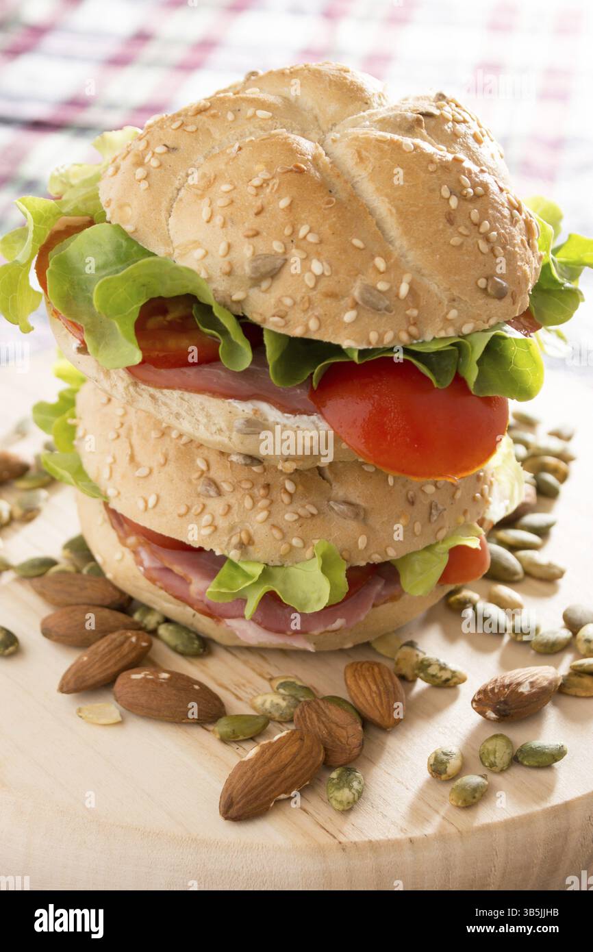 Impilati con panini freschi carne affumicata, formaggio, lattuga e pomodoro con fatti in casa ketchup disposti con mandorle e semi di zucca Foto Stock