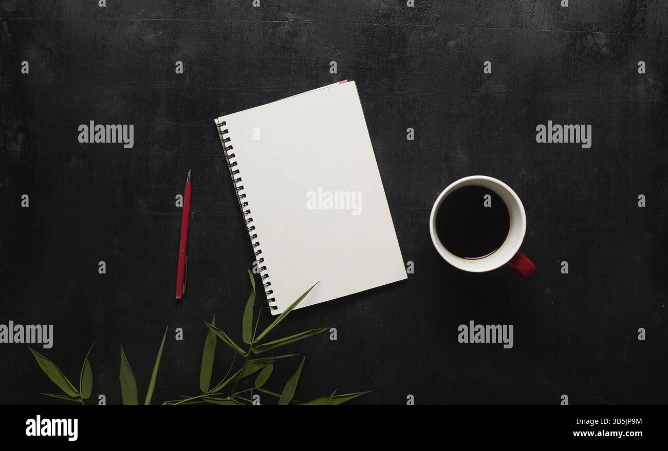 Scrivania da ufficio nera in legno con notebook, penna e tazza di caffè. Pagina vuota del notebook per inserire il testo al centro. Vista dall'alto Foto Stock