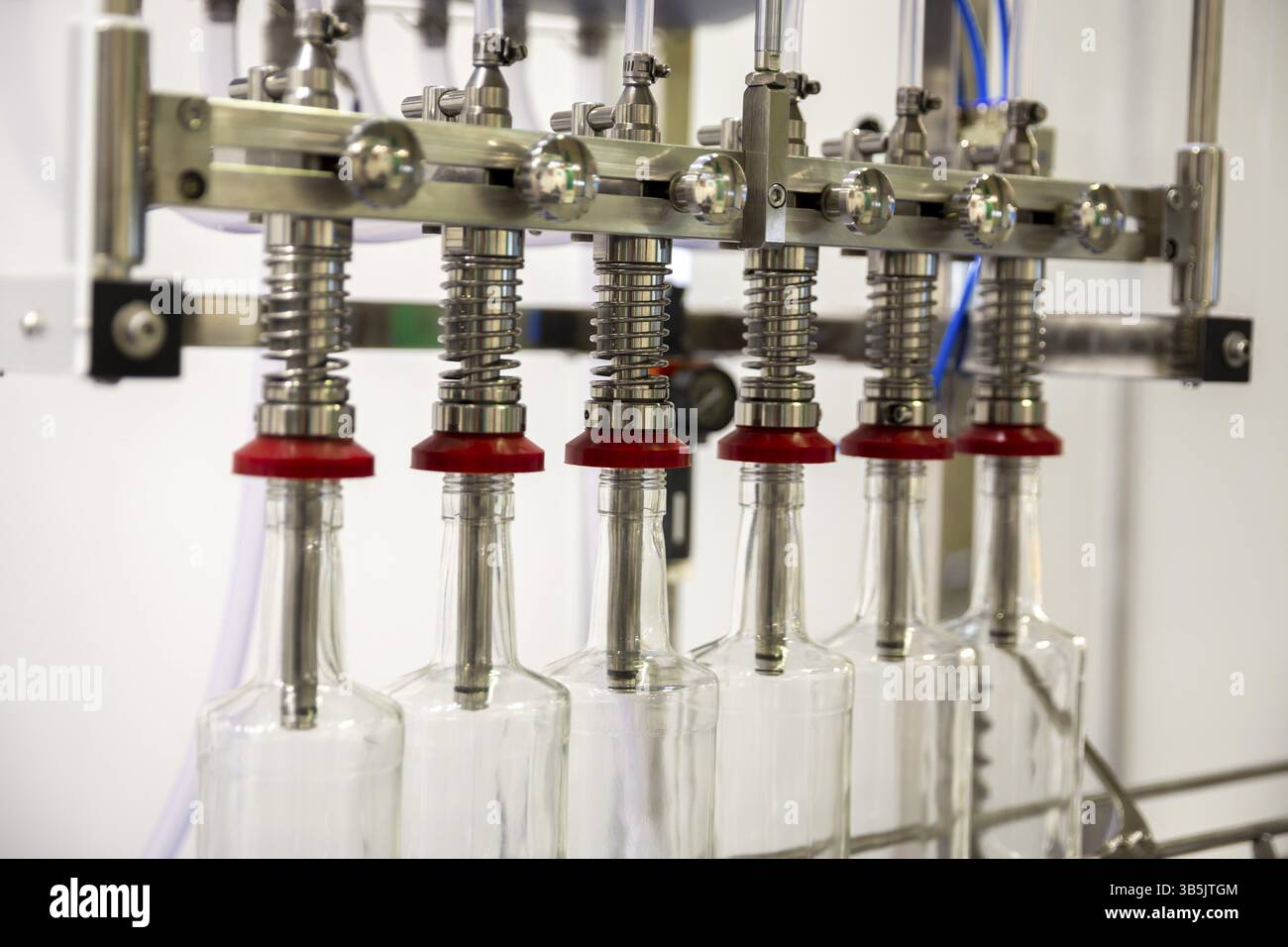 Primo piano di una macchina automatica per il riempimento di bottiglie per uso industriale Foto Stock