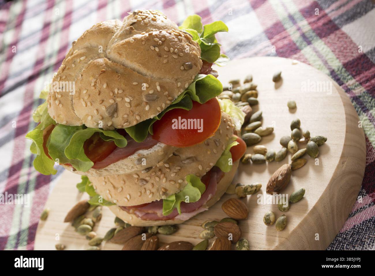 Impilati con panini freschi carne affumicata, formaggio, lattuga e pomodoro con fatti in casa ketchup disposti con mandorle e semi di zucca Foto Stock