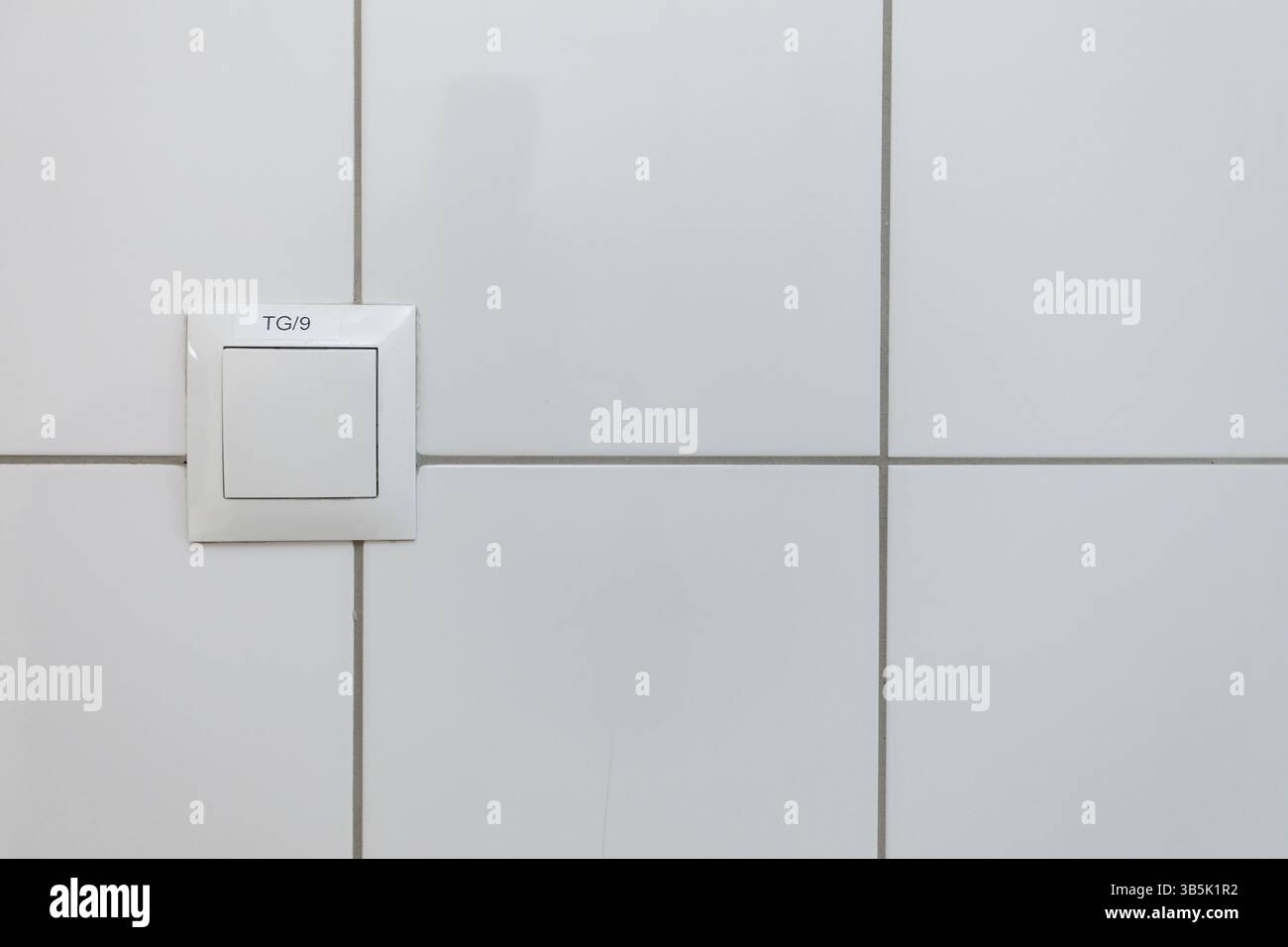Una vista minimalista ed estetica di una parete bianca pulita dotata di una semplice piastra di commutazione per la massima funzionalità Foto Stock