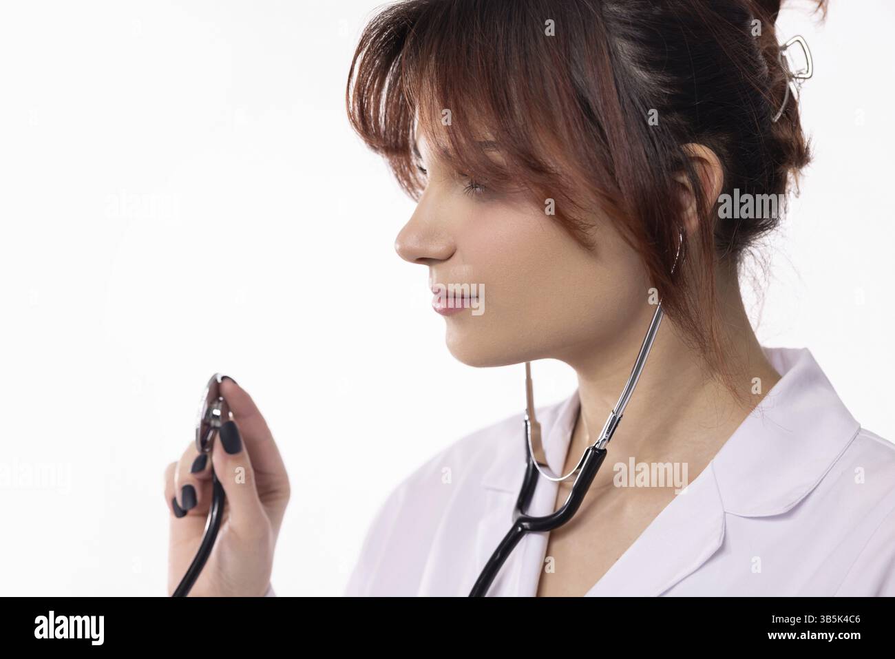 Una donna che si prende cura di lei utilizza uno stetoscopio per valutare la sua paziente, dimostrando la sua professionalità e dedizione Foto Stock