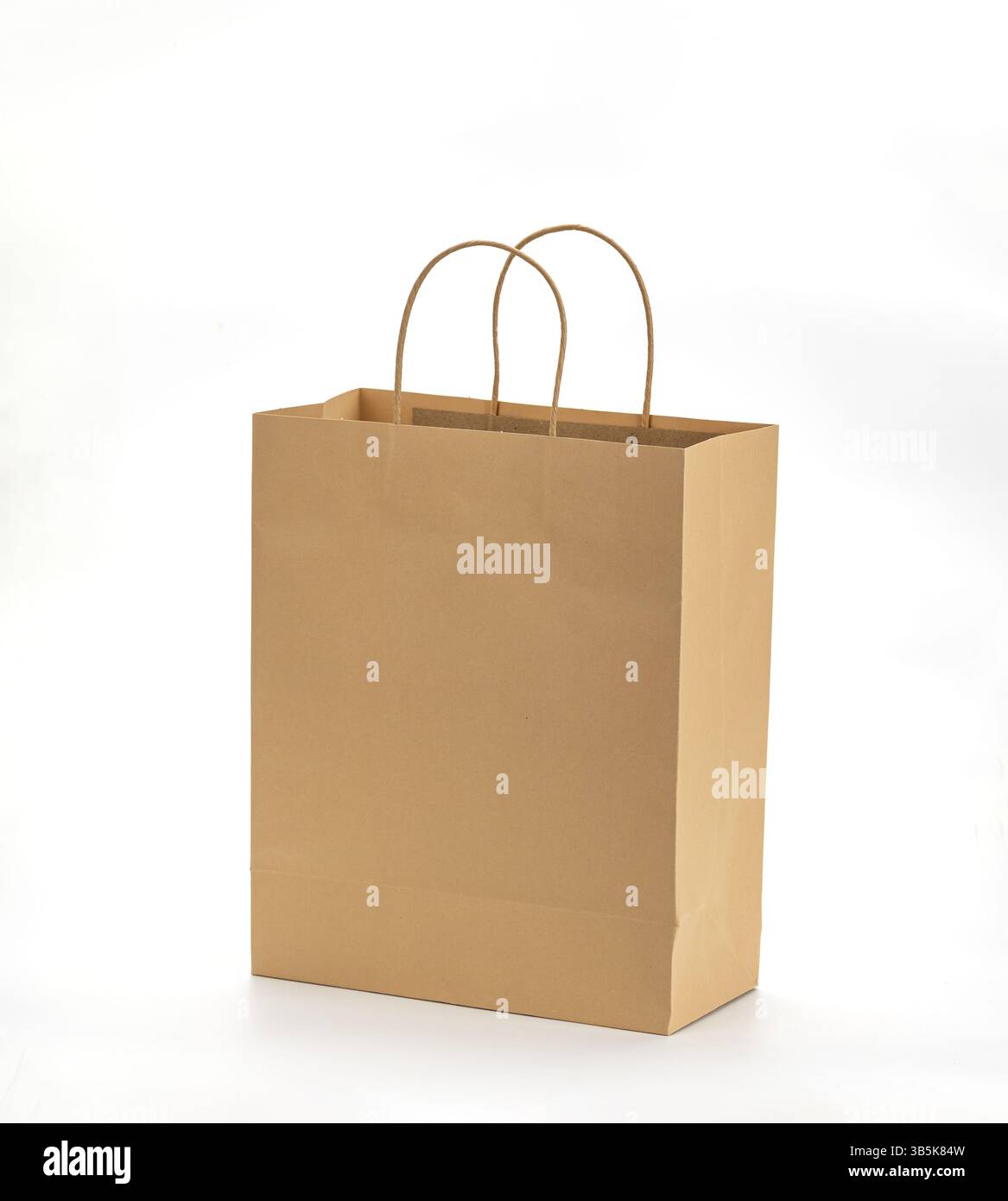 Una borsa per la spesa in carta marrone con manici robusti si staglia su un semplice sfondo bianco, mostrando il suo design ecologico e la sua semplicità Foto Stock