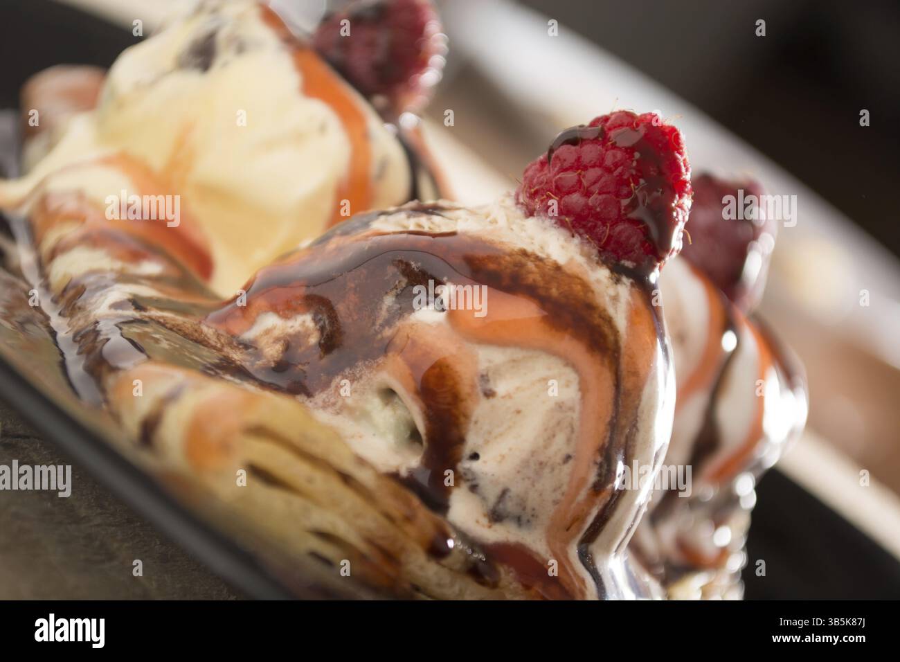 Fresche, golden pancake con frutta e crema su una piastra nera con sfondo sfocato Foto Stock