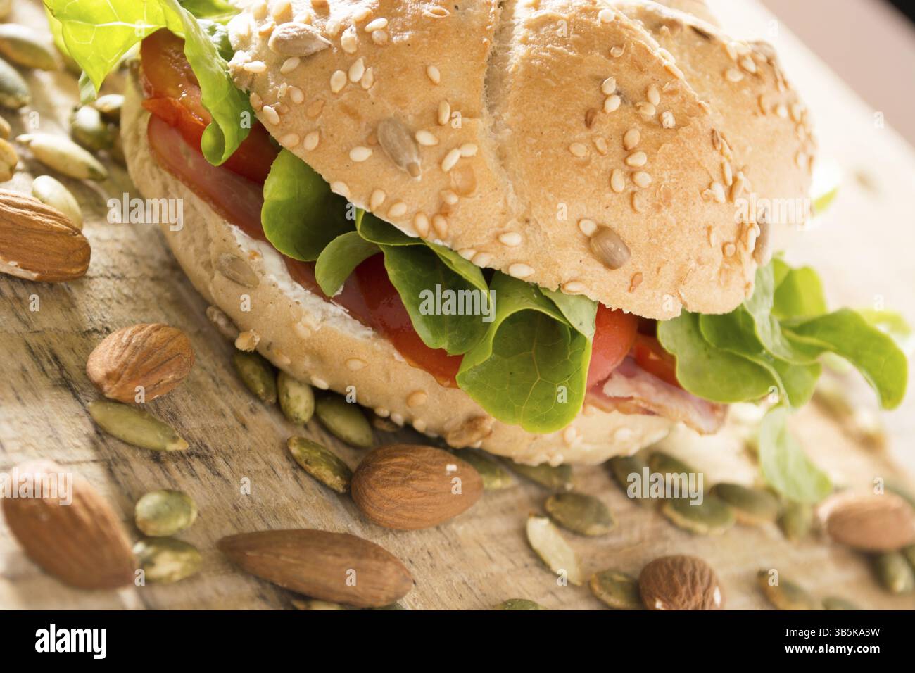 Sandwich freschi con carne affumicata, formaggio, lattuga e pomodoro con fatti in casa ketchup disposti con mandorle e semi di zucca Foto Stock