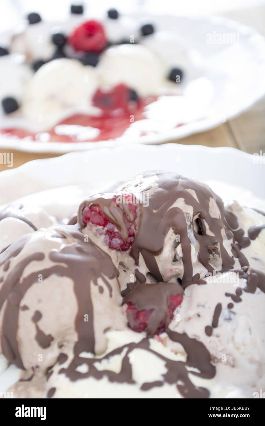 Palline di gelato al cioccolato nella piastra bianca con lamponi e chokeberries Foto Stock