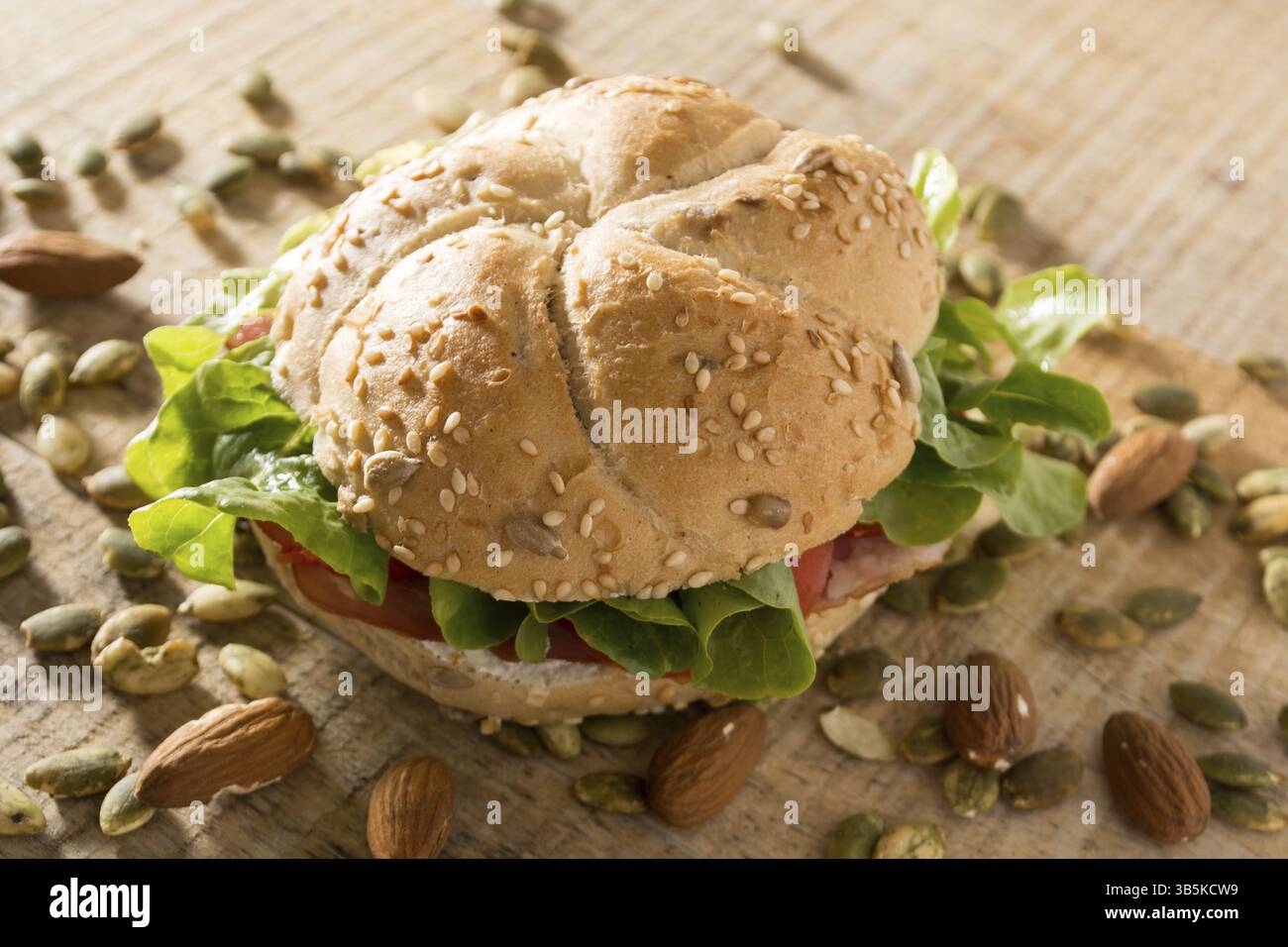 Sandwich freschi con carne affumicata, formaggio, lattuga e pomodoro con fatti in casa ketchup disposti con mandorle e semi di zucca Foto Stock