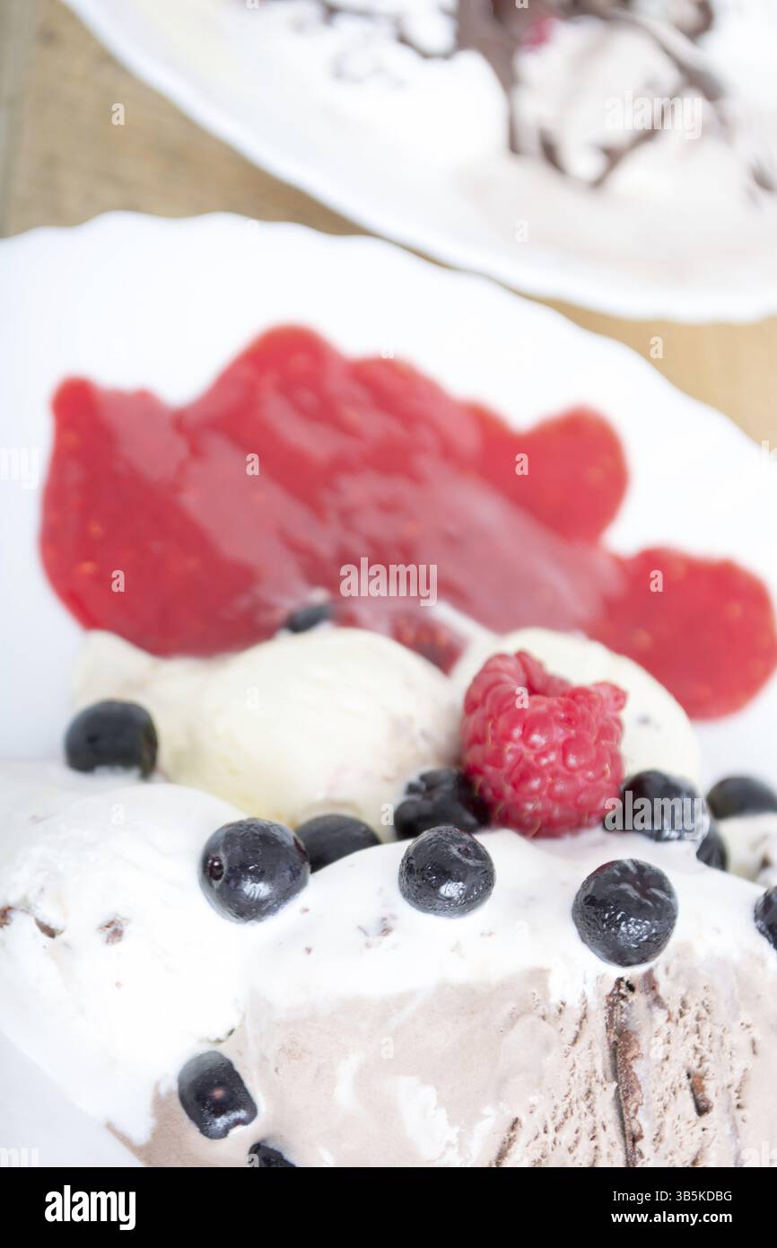 Palline di gelato al cioccolato nella piastra bianca con lamponi e chokeberries Foto Stock