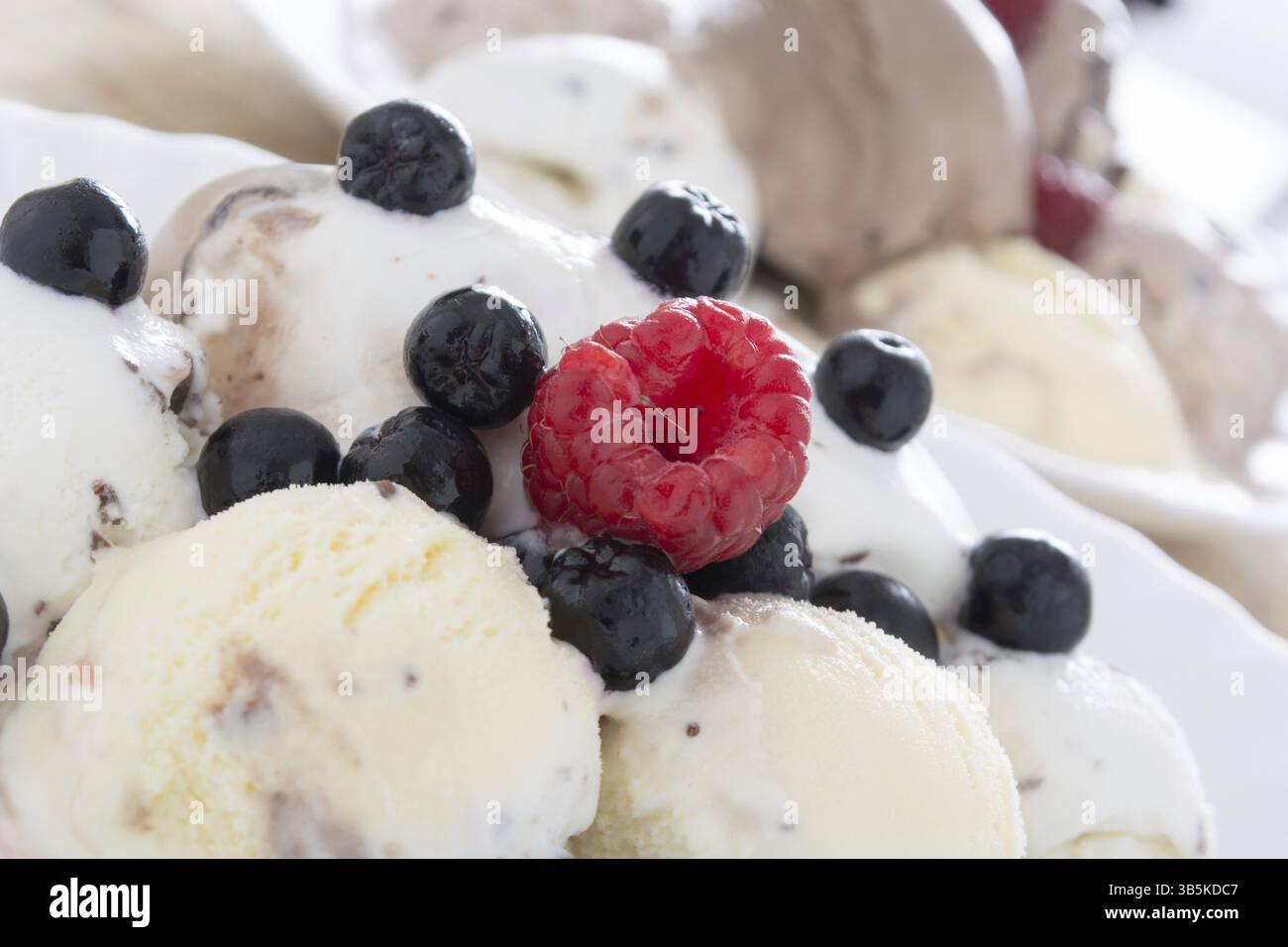 Palline di gelato al cioccolato nella piastra bianca con lamponi e chokeberries Foto Stock