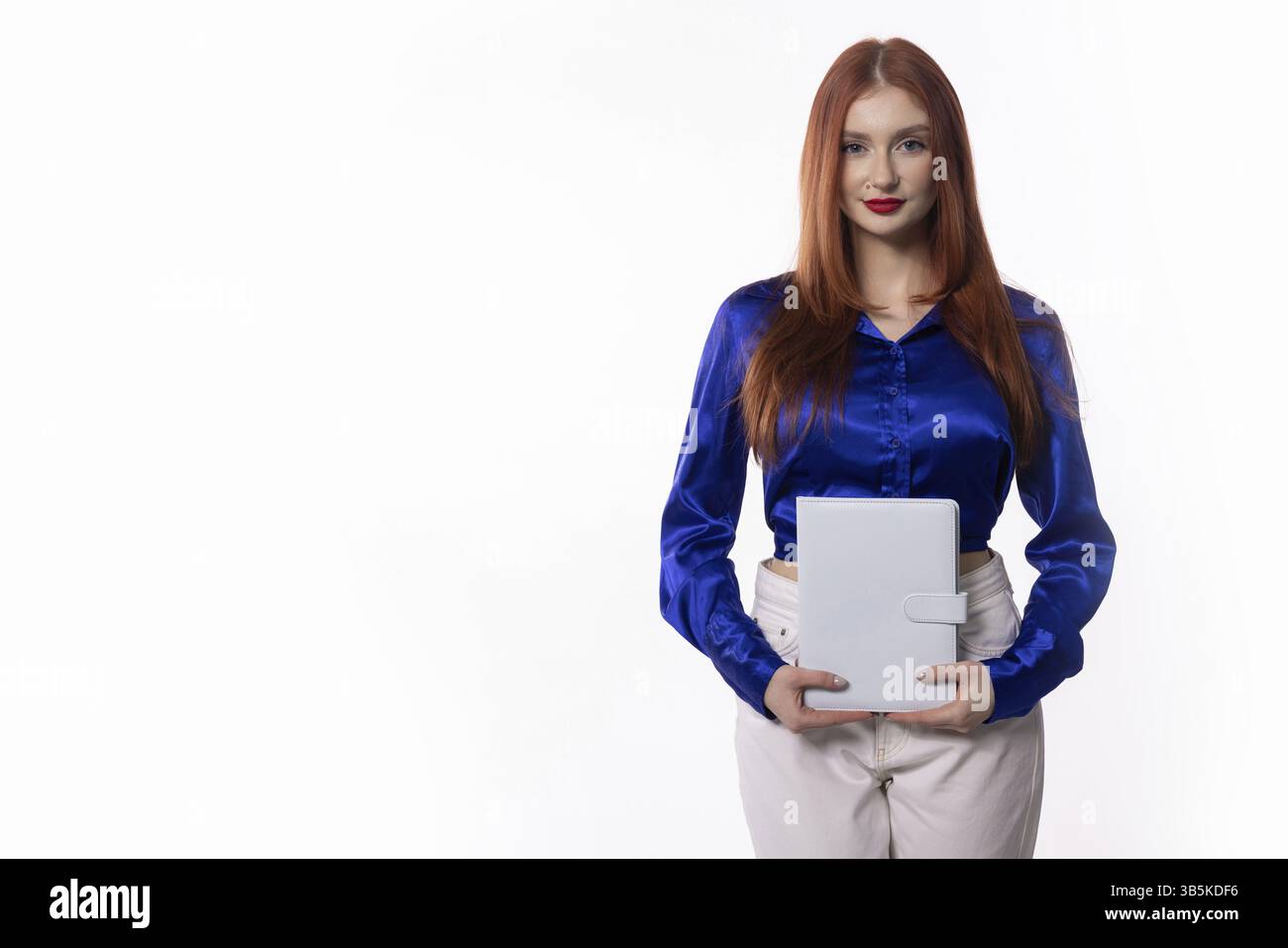 Una donna professionista con un elegante abbigliamento blu ha in mano un tablet, pronto per le riunioni di lavoro Foto Stock