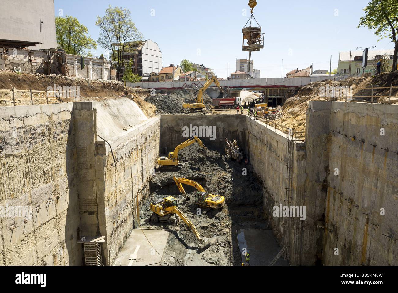 Scavatrici scavare in corrispondenza di un sito di costruzione di una strada e di una fermata della metropolitana. Trasporto Baggers sporco a un livello superiore per fare spazio per la metropolitana di macchina di scavo. Foto Stock
