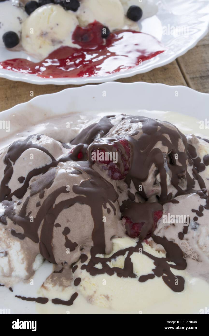 Palline di gelato al cioccolato nella piastra bianca con lamponi e chokeberries Foto Stock