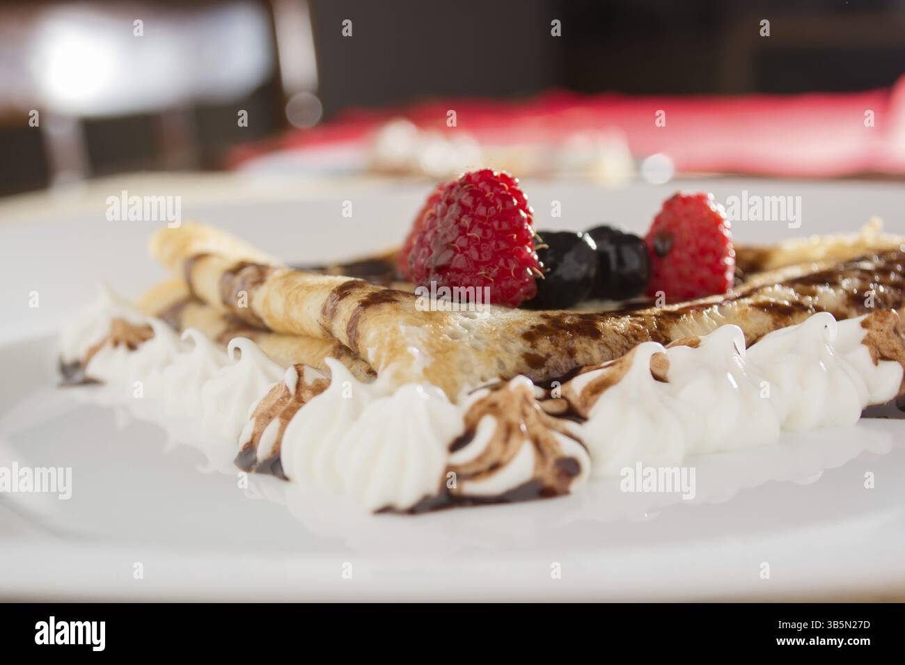 Fresche, golden pancake con frutta e crema su una piastra bianca con sfondo sfocato Foto Stock
