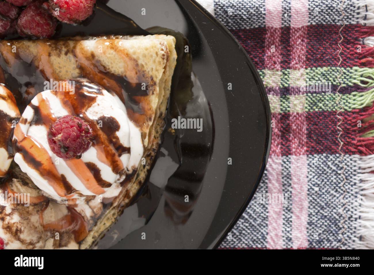 Fresche, golden pancake con frutta e crema su una piastra nera con sfondo sfocato Foto Stock