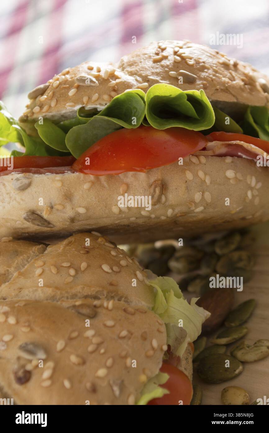Sandwich freschi con carne affumicata, formaggio, lattuga e pomodoro con fatti in casa ketchup disposti con mandorle e semi di zucca Foto Stock