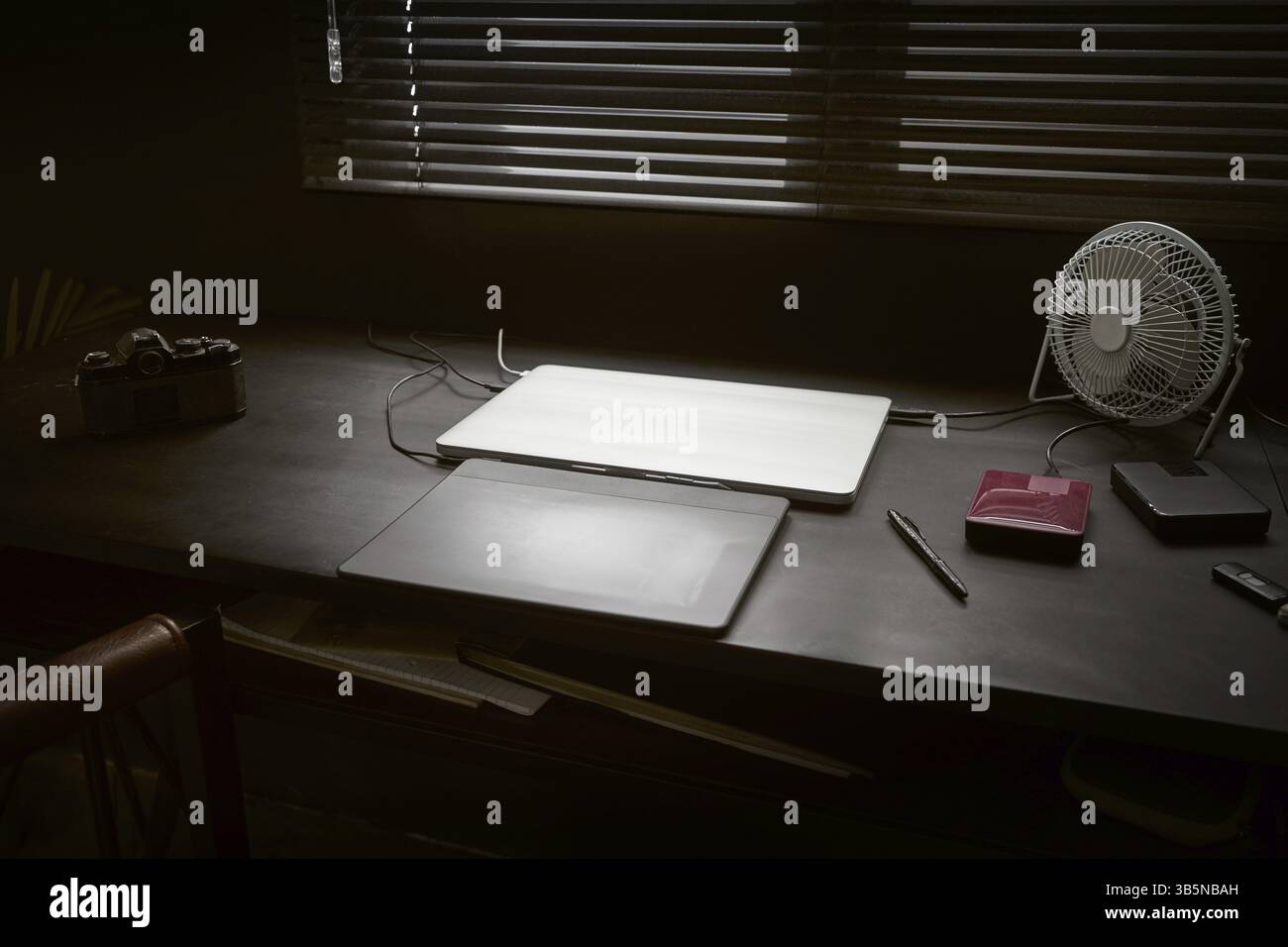 Spazio di lavoro sul tavolo nero di un fotografo o designer con laptop, fotocamera retrò e ventilatore, elegante concetto di hipster in casa. Messa a fuoco selezionata Foto Stock