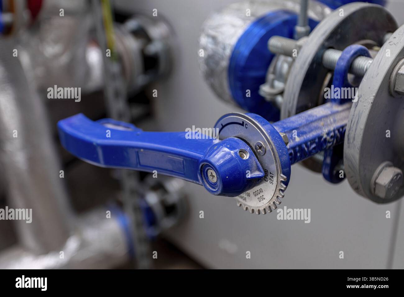 Nahaufnahme eines blauen Ventilgriffs in einer industriellen Umgebung, die seine Bedeutung und Funktion hervorhebt Foto Stock