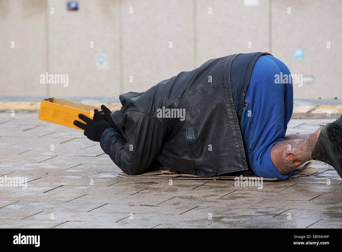 Senzatetto uomo con gamba male sulle sue ginocchia mendica per denaro presso la strada. Dieci anni dopo l' ingresso nell' Unione europea la Bulgaria è ancora il paese più povero dell'Unio Foto Stock
