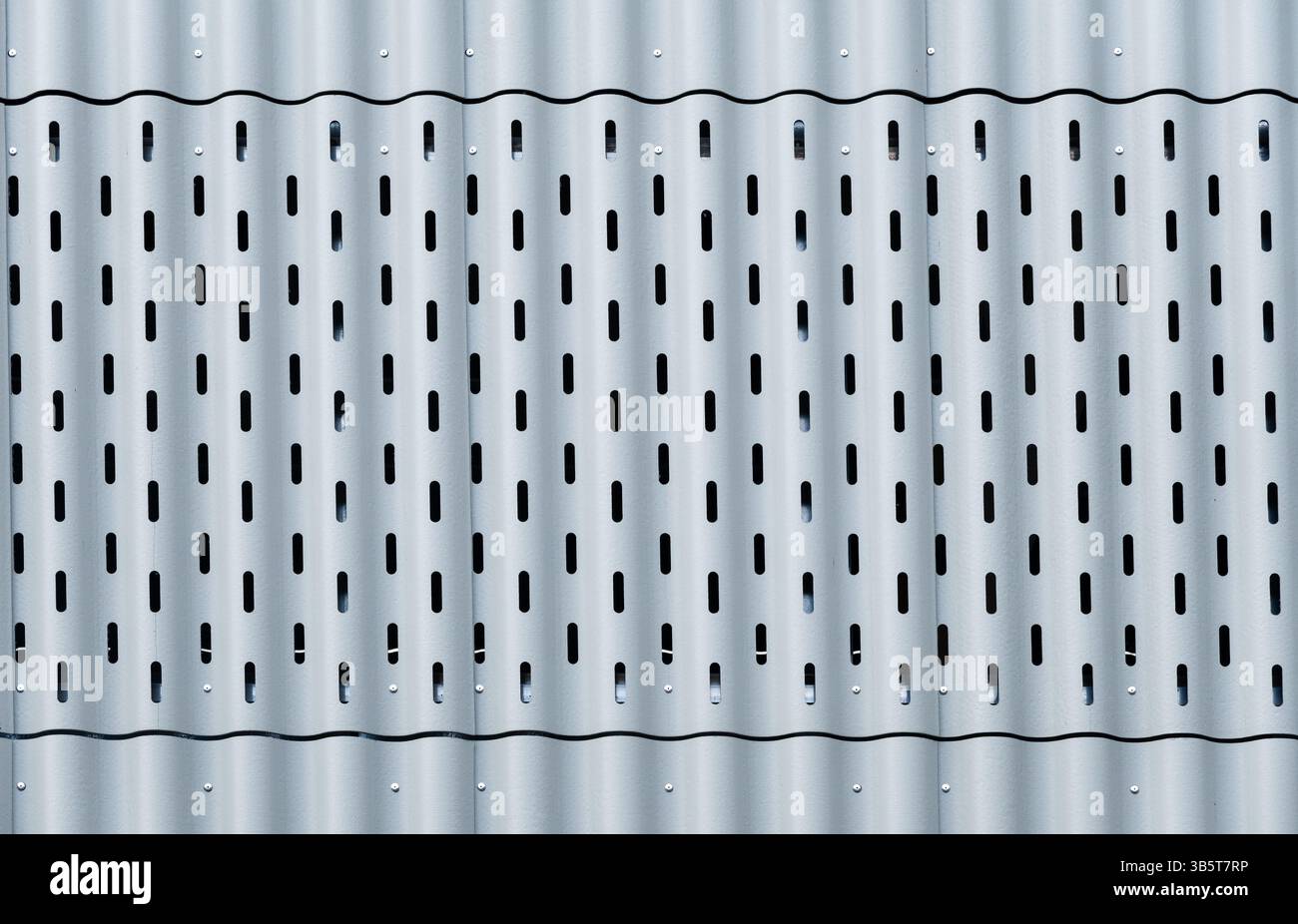 Lamiera ondulata metallica con motivo perforato, grigio chiaro, moderno design industriale. Foto Stock