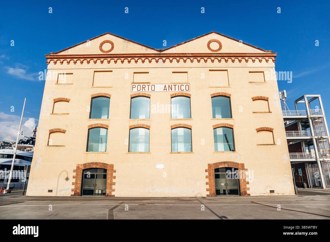 Genova, Italia - 22 settembre 2024: Lungomare di Porto Antico con barche, attrazioni moderne ed edifici storici sotto un cielo limpido. Foto Stock