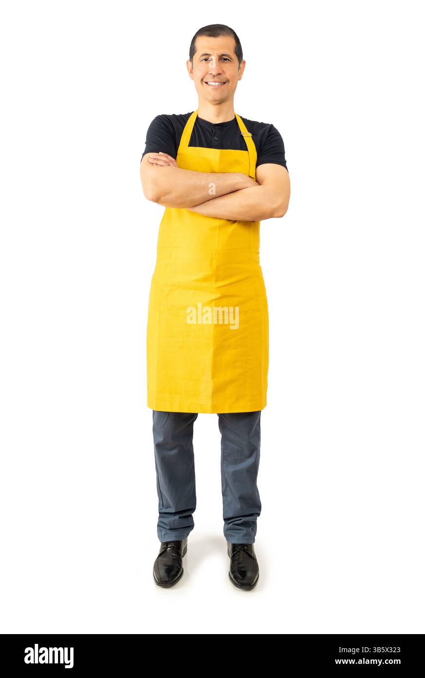 Ripresa completa di un dipendente sicuro dell'ipermercato con le braccia incrociate e grembiule giallo su sfondo bianco Foto Stock