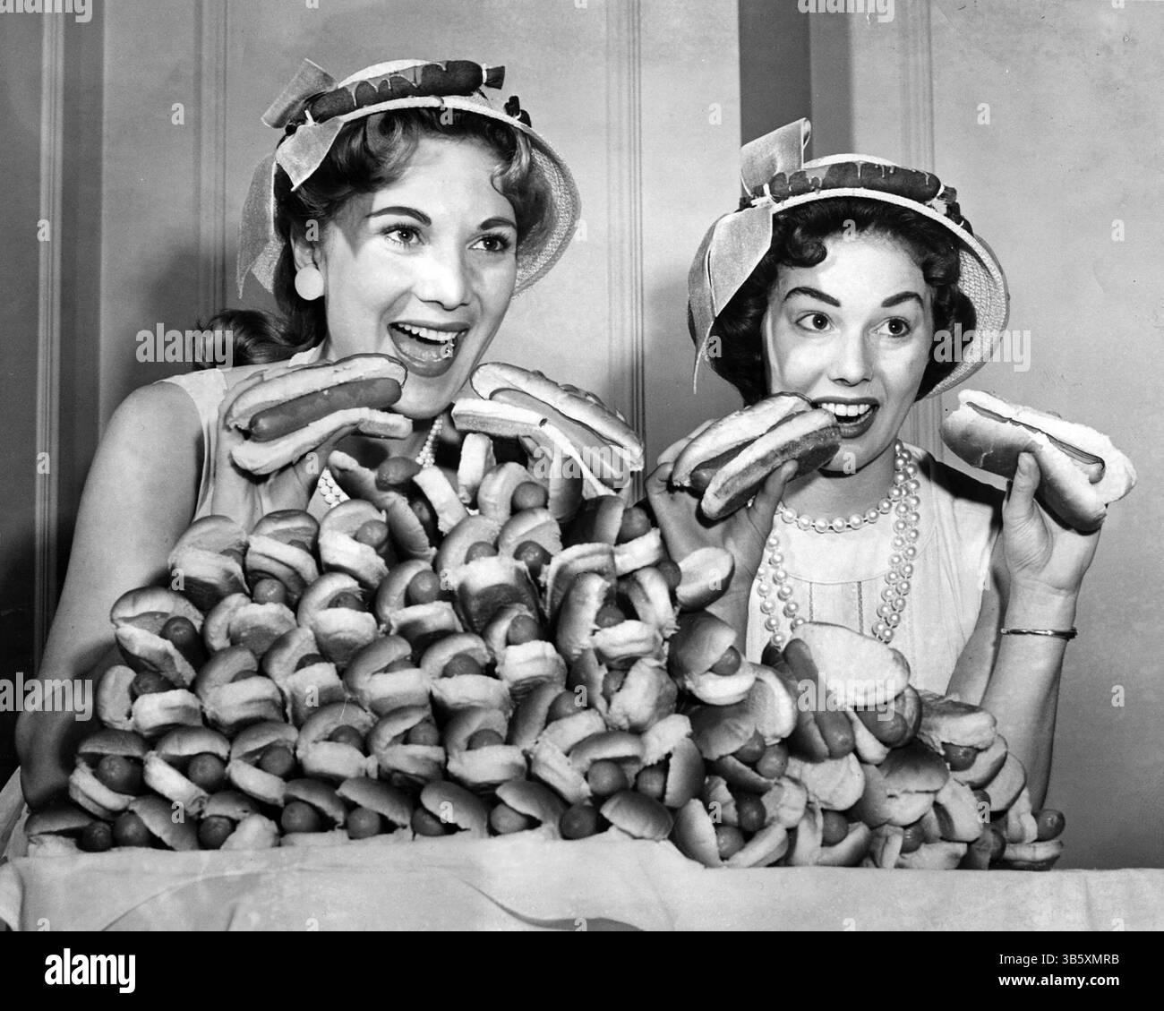 17 giugno 2022: Marion Todd, Left e Marge Kraus di Chicago furono ambasciatori durante il National Hot Dog Month nel luglio 1957 e fecero un tour della nazione per promuovere l'amato frankfurter. Qui posero con un piatto di 60 hot dog, che all'epoca rappresentavano ciò che l'americano medio mangiava in un anno. I loro bei cappelli erano impreziositi da una banda di hot dog soffocati di senape. (Immagine di credito: © Chicago Tribune Historical/Chicago Tribune/TNS via ZUMA Press Wire) Foto Stock