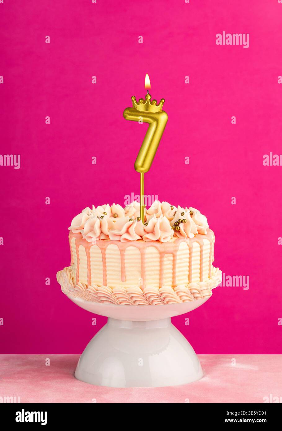La candela di compleanno numero 7 - torta rosa per festeggiare con glassa a goccia Foto Stock