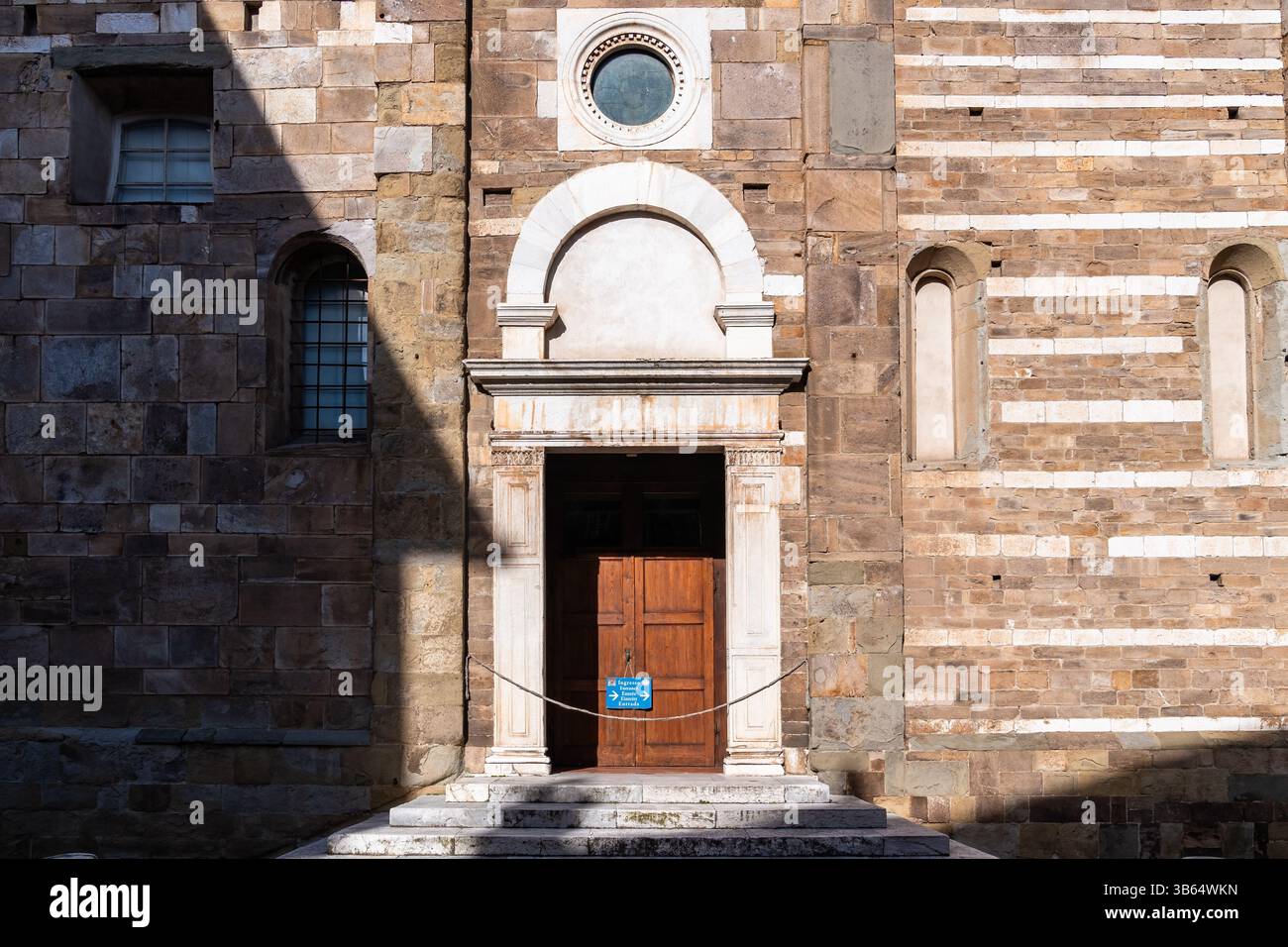 Lucca, Italia - 16 febbraio 2025: Porta laterale della Basilica di San Frediano a Lucca durante una giornata di sole Foto Stock