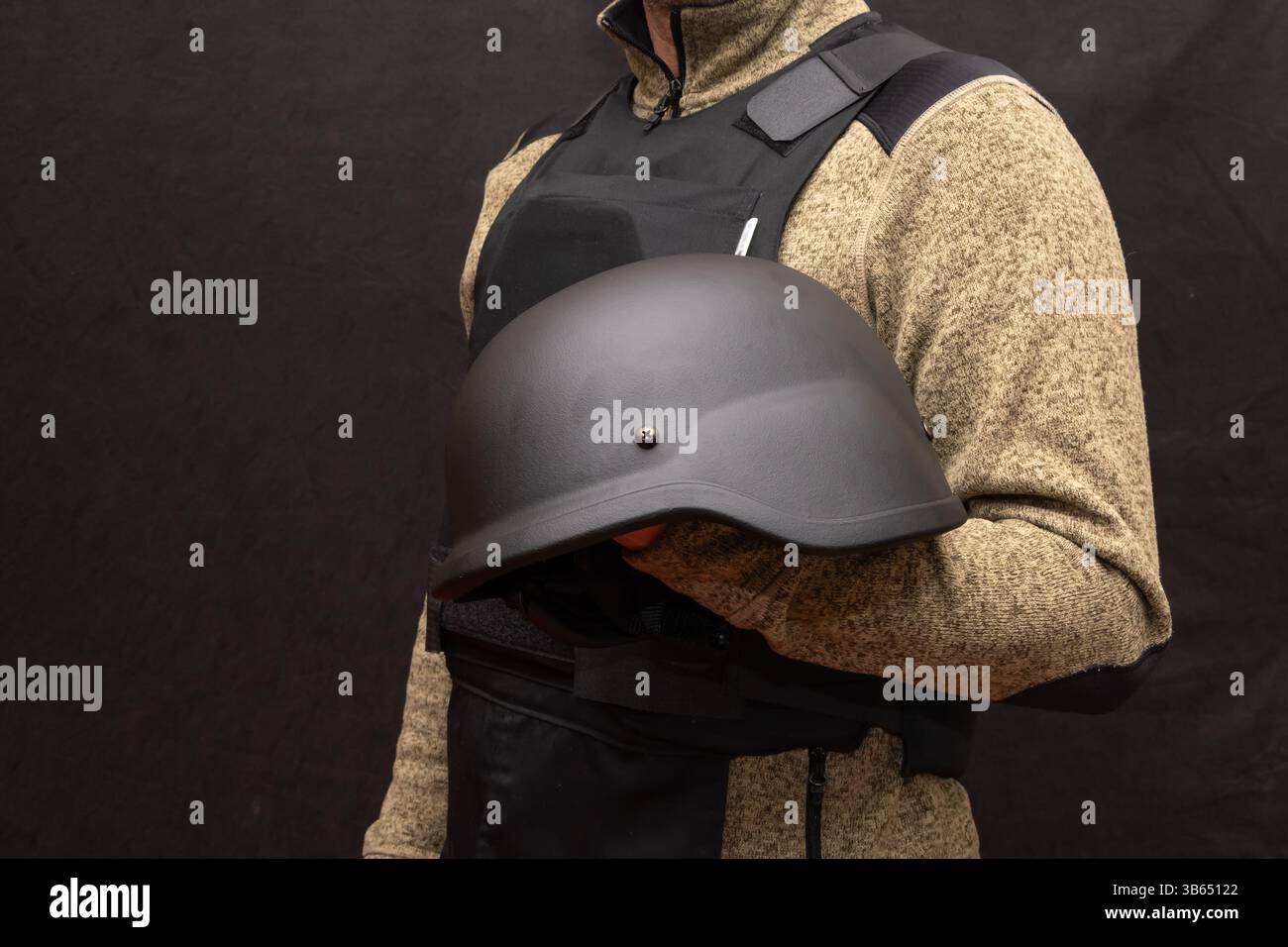 Un membro del personale con l'attrezzatura protettiva mostra un casco balistico. Adatto per temi di sicurezza, tattici, militari o forze speciali Foto Stock
