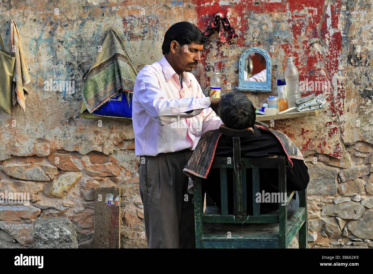 Jaipur, Rajasthan, India settentrionale, India, Asia, parrucchiere tradizionale che lavora su un cliente in un angolo di strada improvvisato, in Asia Foto Stock