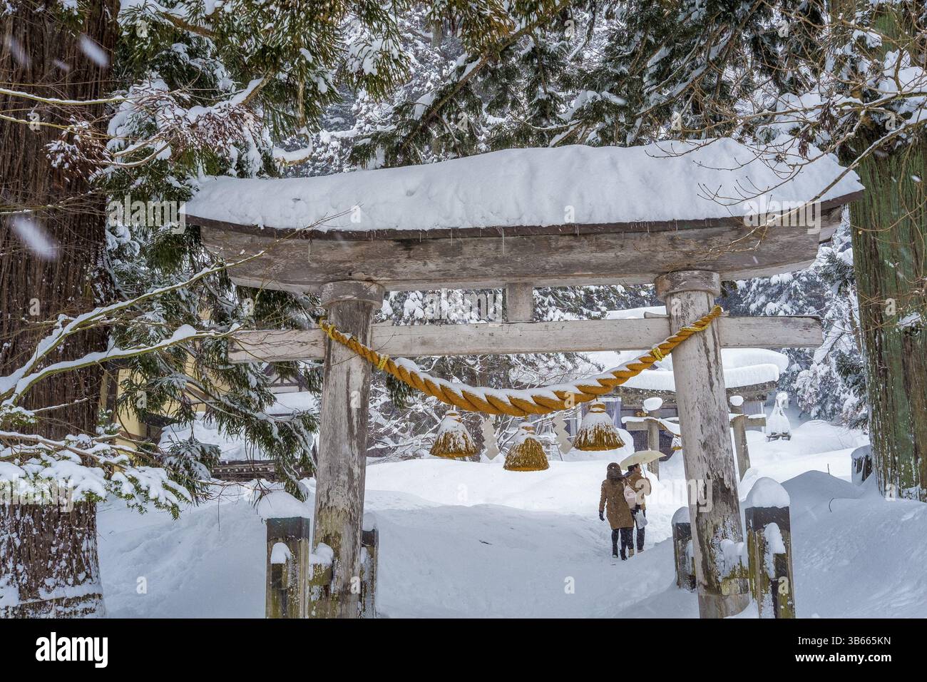 Porta Torii coperta di neve di fronte al santuario shintoista in inverno Foto Stock