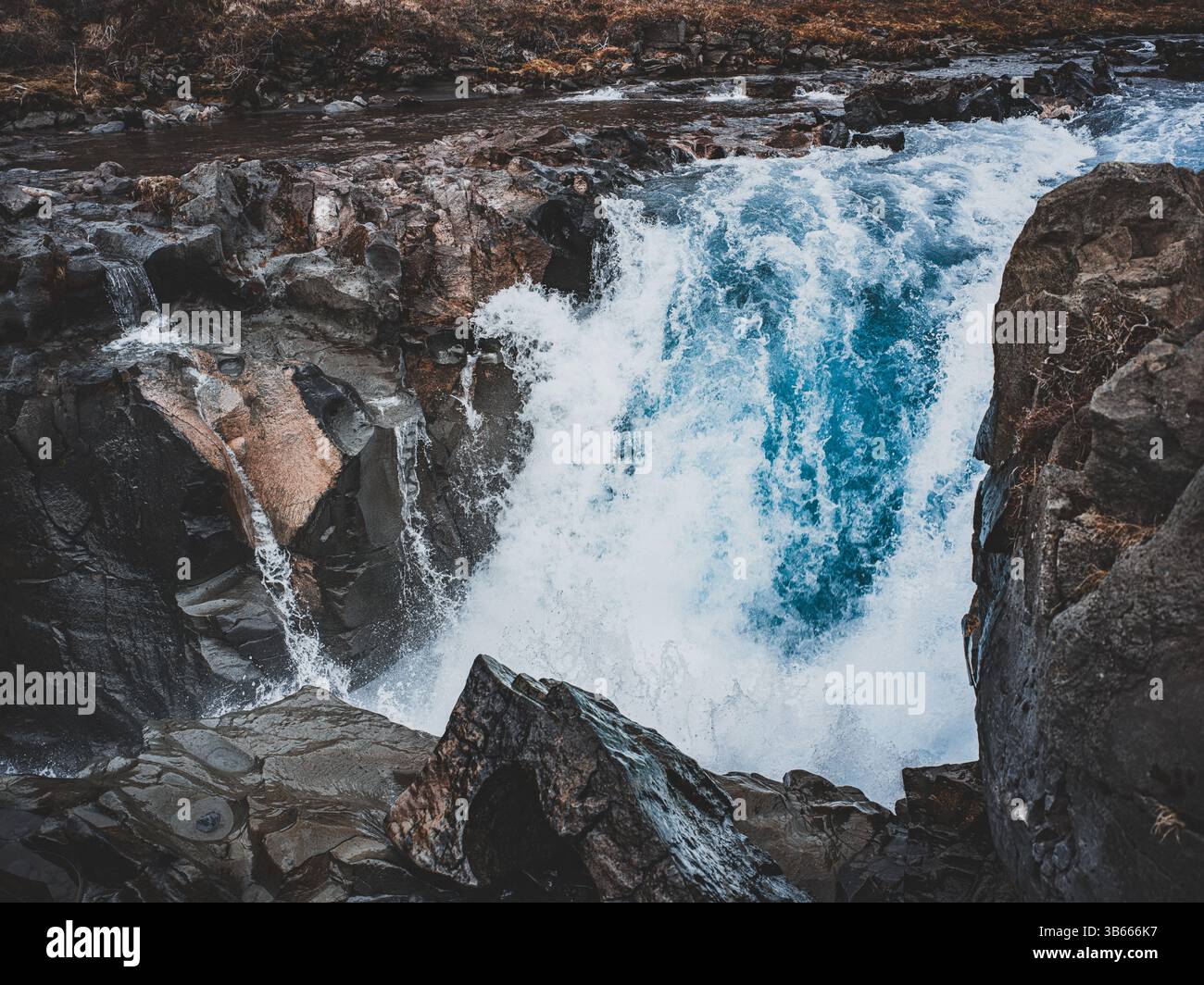 Potente cascata islandese che scorre attraverso le rocce vulcaniche in uno stretto canyon Foto Stock