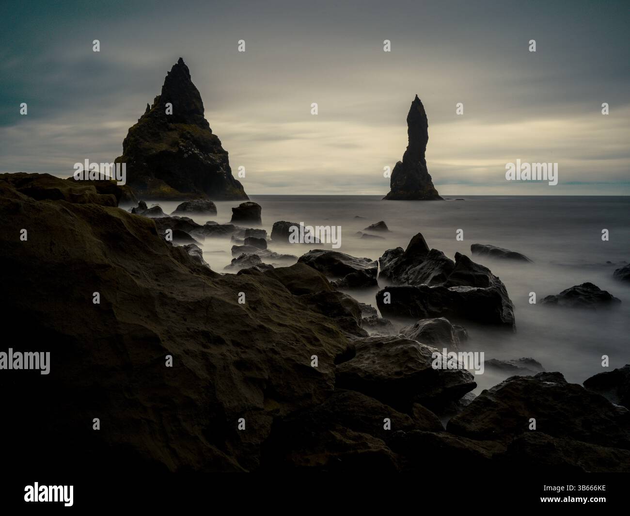 Le montagne marine di Reynisdrangar emergono dalle onde nebbiose sulla spiaggia di Reynisfjara, nel sud dell'Islanda Foto Stock