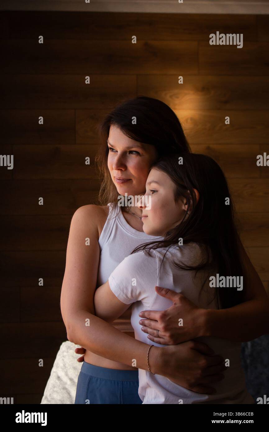 Amore generazionale. Mamma e figlia si abbracciano a vicenda. Le tradizioni familiari sono passate attraverso l'abbraccio. Eredità, genitorialità, concetto d'infanzia. Verticale Foto Stock