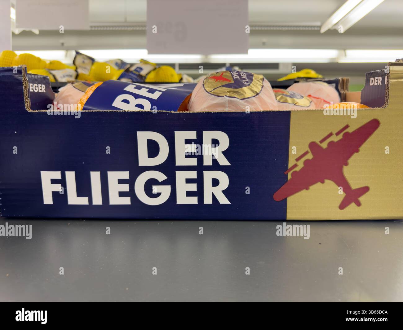 Norimberga, Germania, 2024 gennaio 24: Tiro ad angolo basso di una scatola di prodotti etichettata "Der Flieger" piena di arance, limoni e altri prodotti confezionati in A. Foto Stock