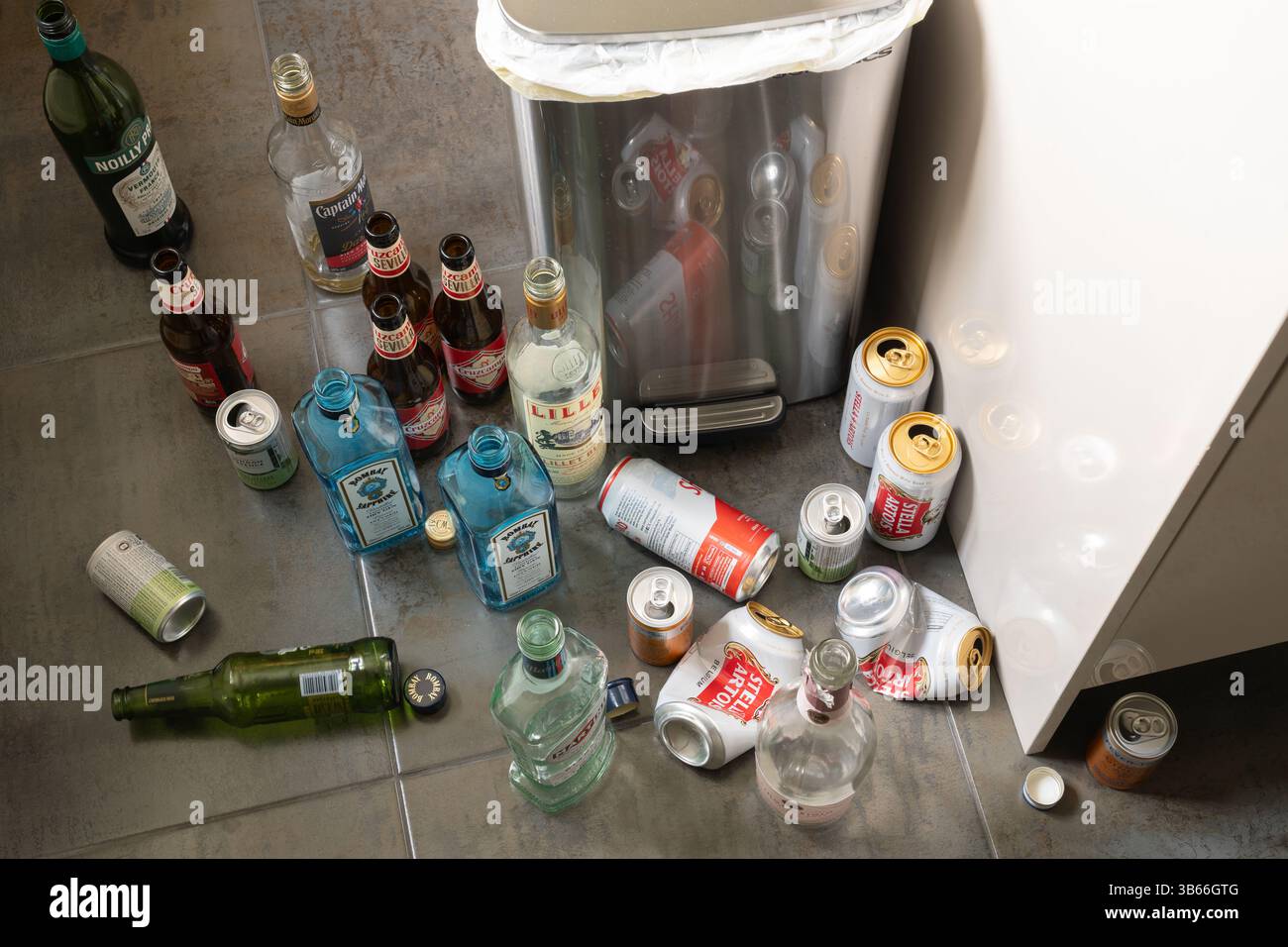 Lattine di birra vuote e bottiglie di alcolici su un piano di cucina vicino a un bidone, in Inghilterra. Concetto: Alcolismo funzionante, alcolismo, dipendenza, vita sprecata Foto Stock