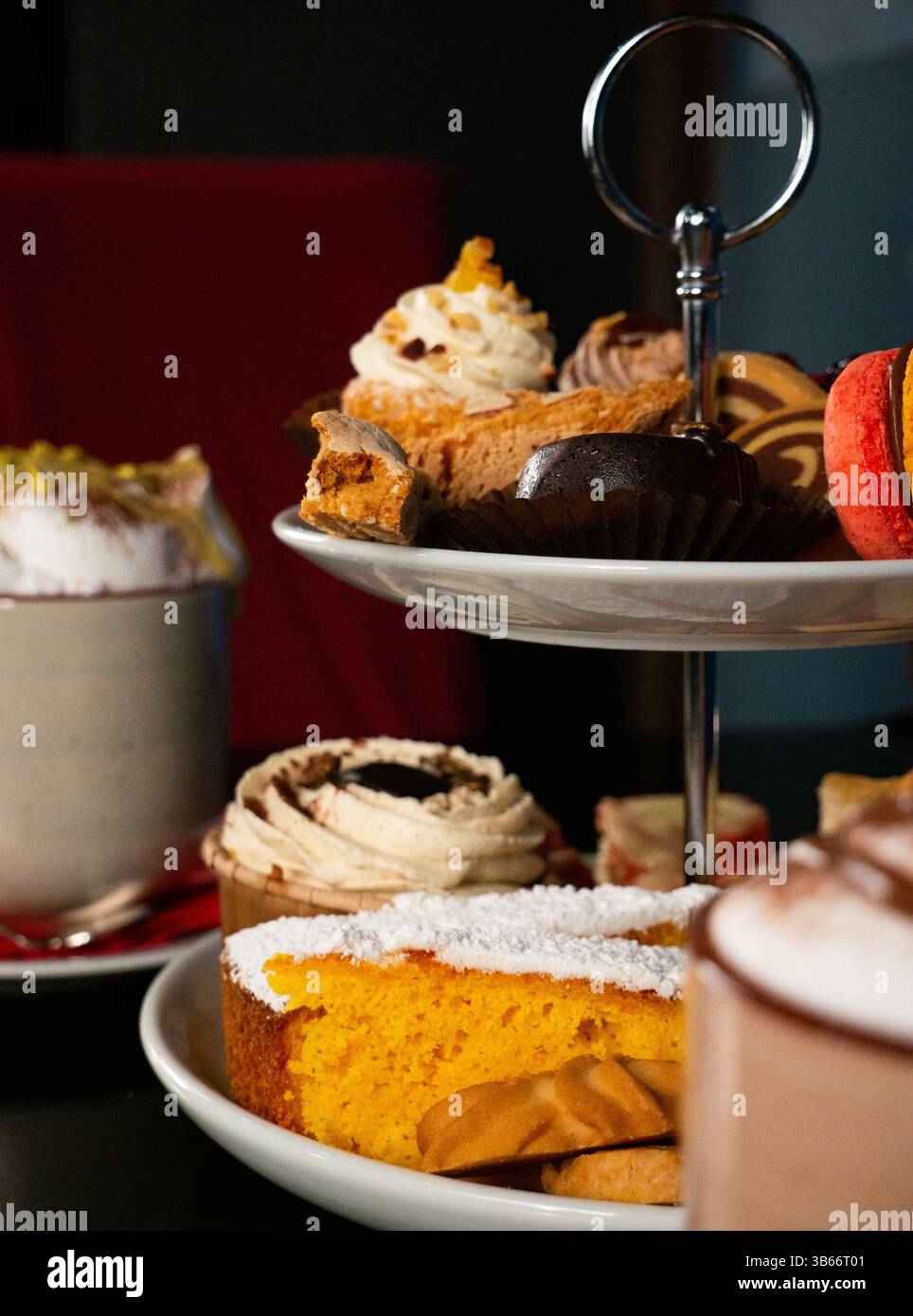 Un dettagliato primo piano di uno stand a due piani pieno di una varietà di piccoli ed eleganti dessert, tra cui cupcake, pasticcini e biscotti. Foto Stock