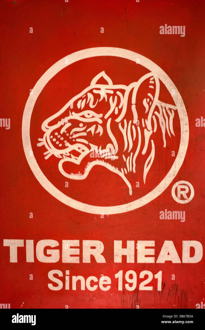 Murale vintage dipinto a mano con il logo Tiger Head con illustrazione stilizzata di tigre e testo "Since 1921", trovato su un muro di strada nella Vecchia Dacca. Foto Stock