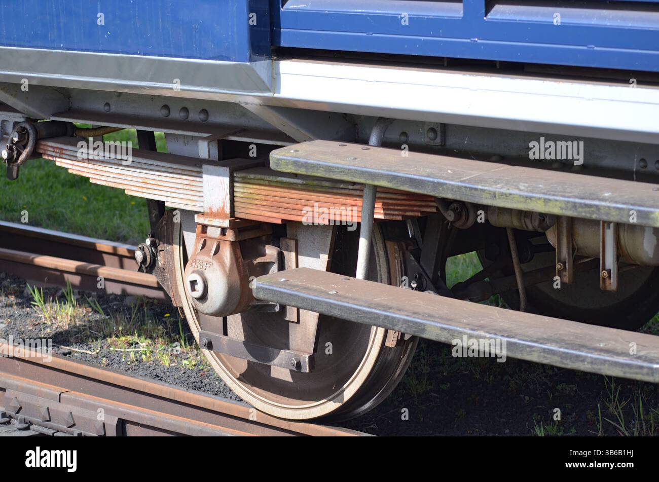 Vista ravvicinata di un complessivo ruota del treno d'epoca che mostra intricati componenti metallici e dettagli ruggine, mettendo in evidenza l'ingegneria dietro la ferrovia Foto Stock