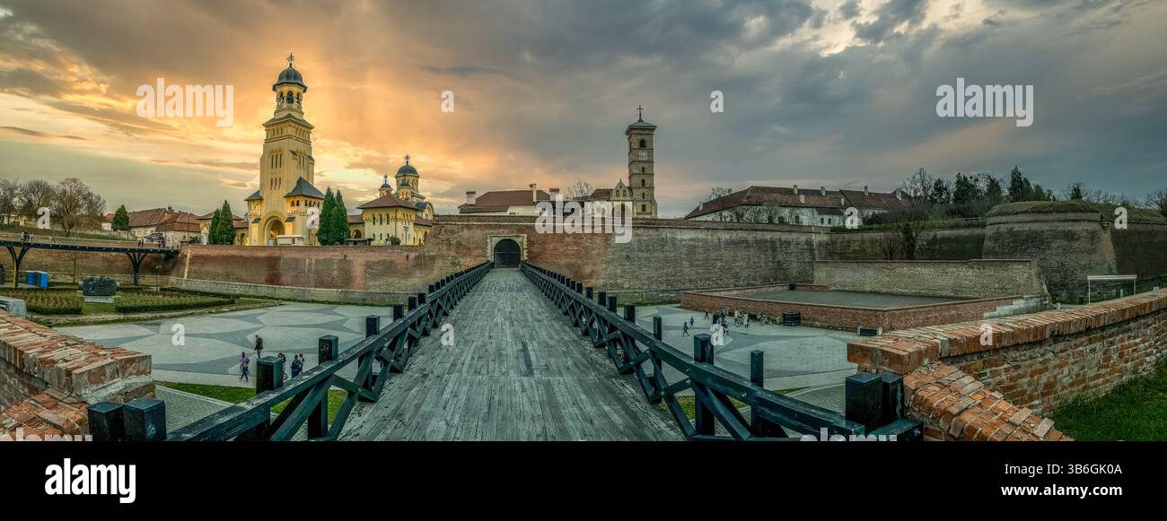 Vista della fortezza di Alba Iulia in Romania con cielo al tramonto, bastioni, cancelli con ponte di legno sul fossato e chiesa Ortodox della Cattedrale dell'Incoronazione Foto Stock