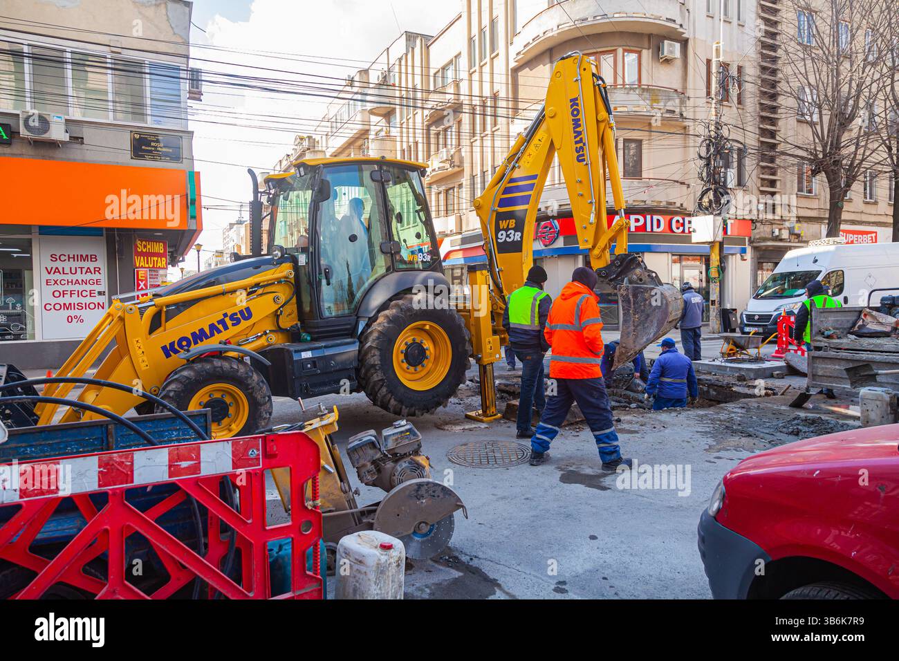Il lavoro dei servizi pubblici sulla posa delle comunicazioni nel terreno con l'aiuto di un trattore di movimento terra in Foto Stock