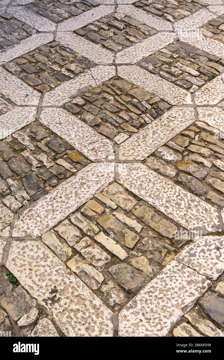 Lavorazioni complesse in pietra che creano un design geometrico su un percorso, mettendo in mostra la maestria artigianale e creando interesse visivo Foto Stock