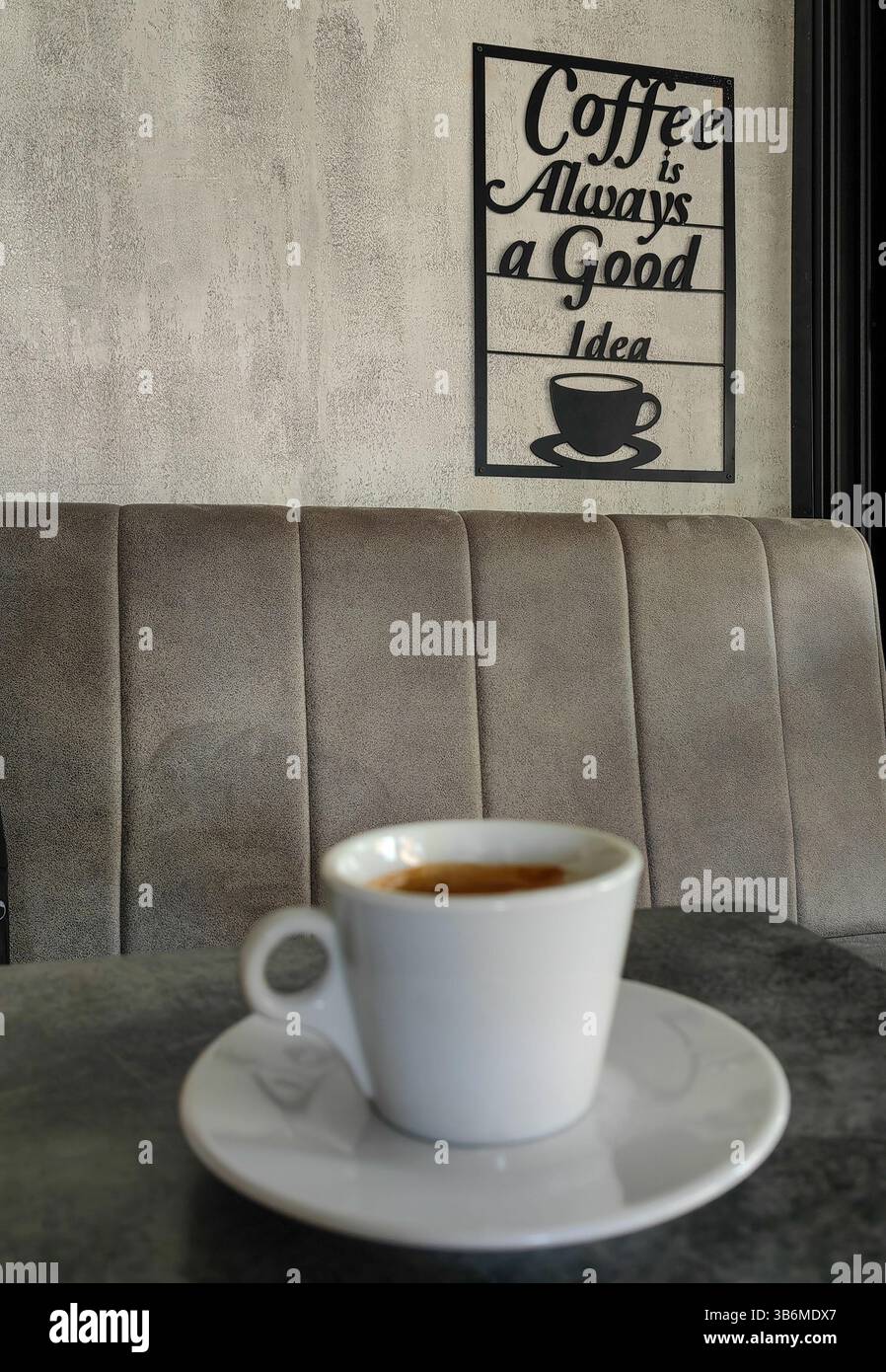 Erogazione confortevole. Il caffè è sempre una buona idea, segnaletica sull'interno grigio della parete. Lettere nere. Foto Stock