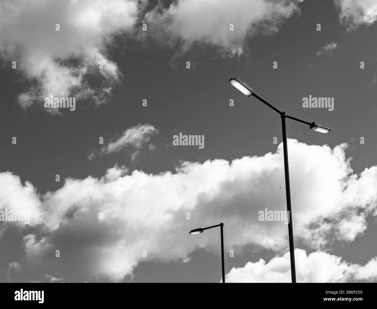 Lampioni che illuminano durante il giorno con sfondo cielo nuvoloso Foto Stock