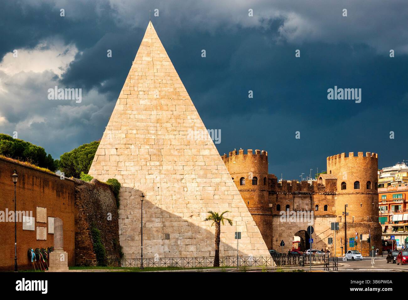 Vista della Piramide di Cestio e di porta San Paolo a Roma, in Italia, sotto cieli bui prima di una tempesta.​ Foto Stock