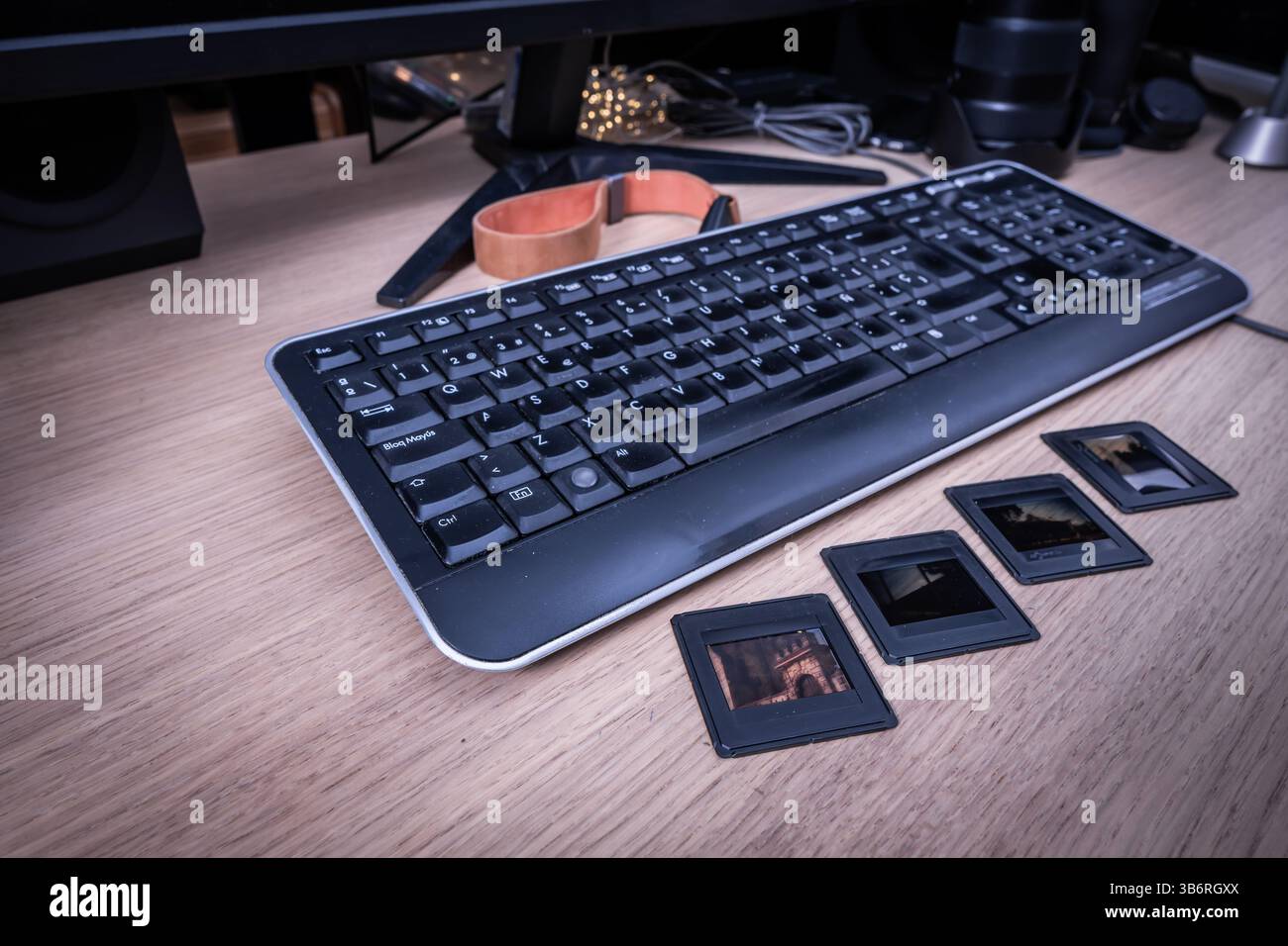 Tastiera per computer retrò e diapositive fotografiche posizionate su una scrivania in legno con monitor sullo sfondo, che mostrano il passaggio dalla fotografia analogica a quella digitale Foto Stock