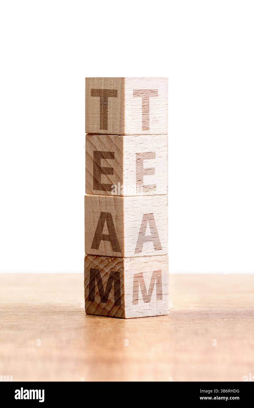 Quattro blocchi di legno sono impilati ordinatamente su una superficie di legno chiaro, ognuno con la parola "TEAM" che enfatizza la collaborazione e l'unità in un semplice voi Foto Stock