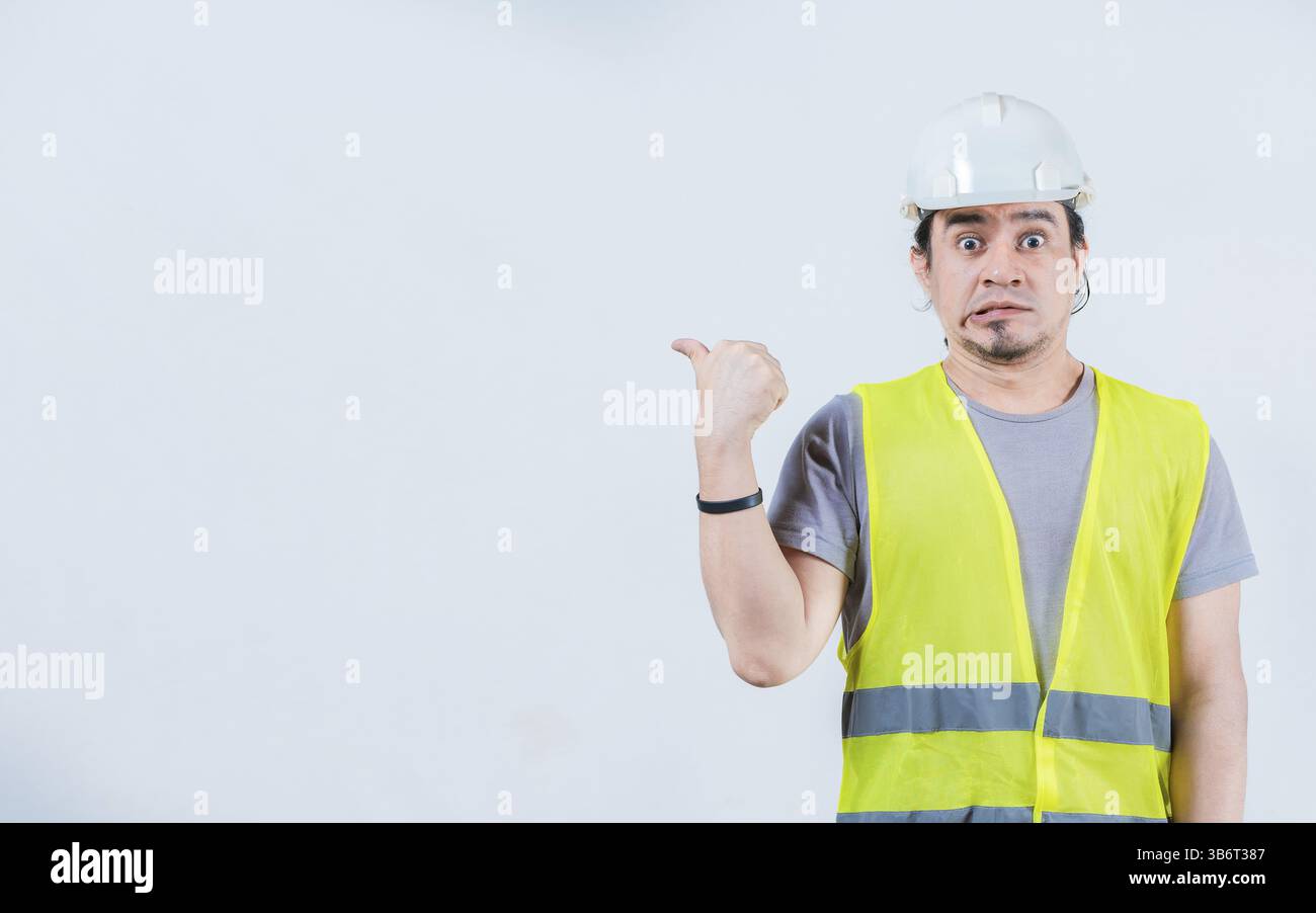 Il costruttore ha sorpreso a indicare uno spazio pubblicitario isolato. Stupito operaio edile che ha puntato su uno spazio vuoto isolato Foto Stock