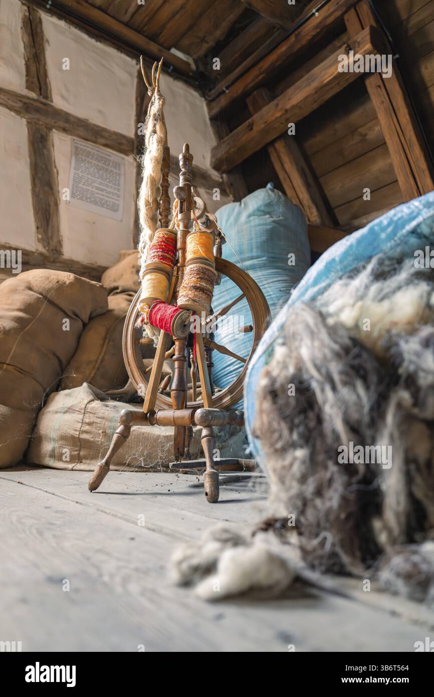 Ruota rotante tradizionale circondata da materiali simili alla lana in una stanza rustica, Museo della conceria di vitello, Foresta Nera, Germania, Europa Foto Stock